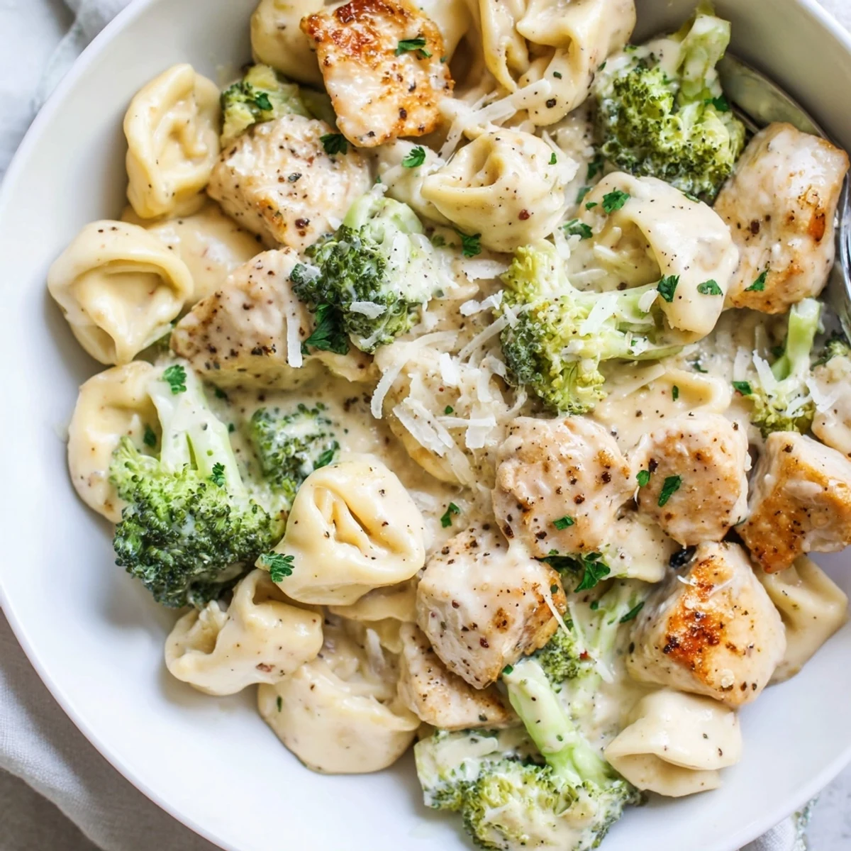 Skillet ready Creamy Garlic Parmesan Tortellini Chicken Broccoli Recipe, silky sauce clinging to pasta.
