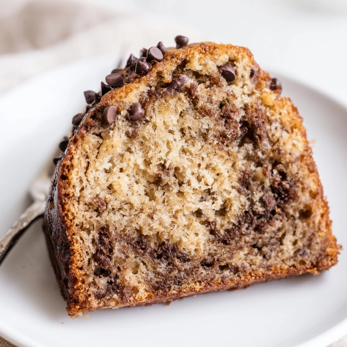 Moist Banana Chocolate Chip Cake Recipe steaming from oven, speckled with chocolate.