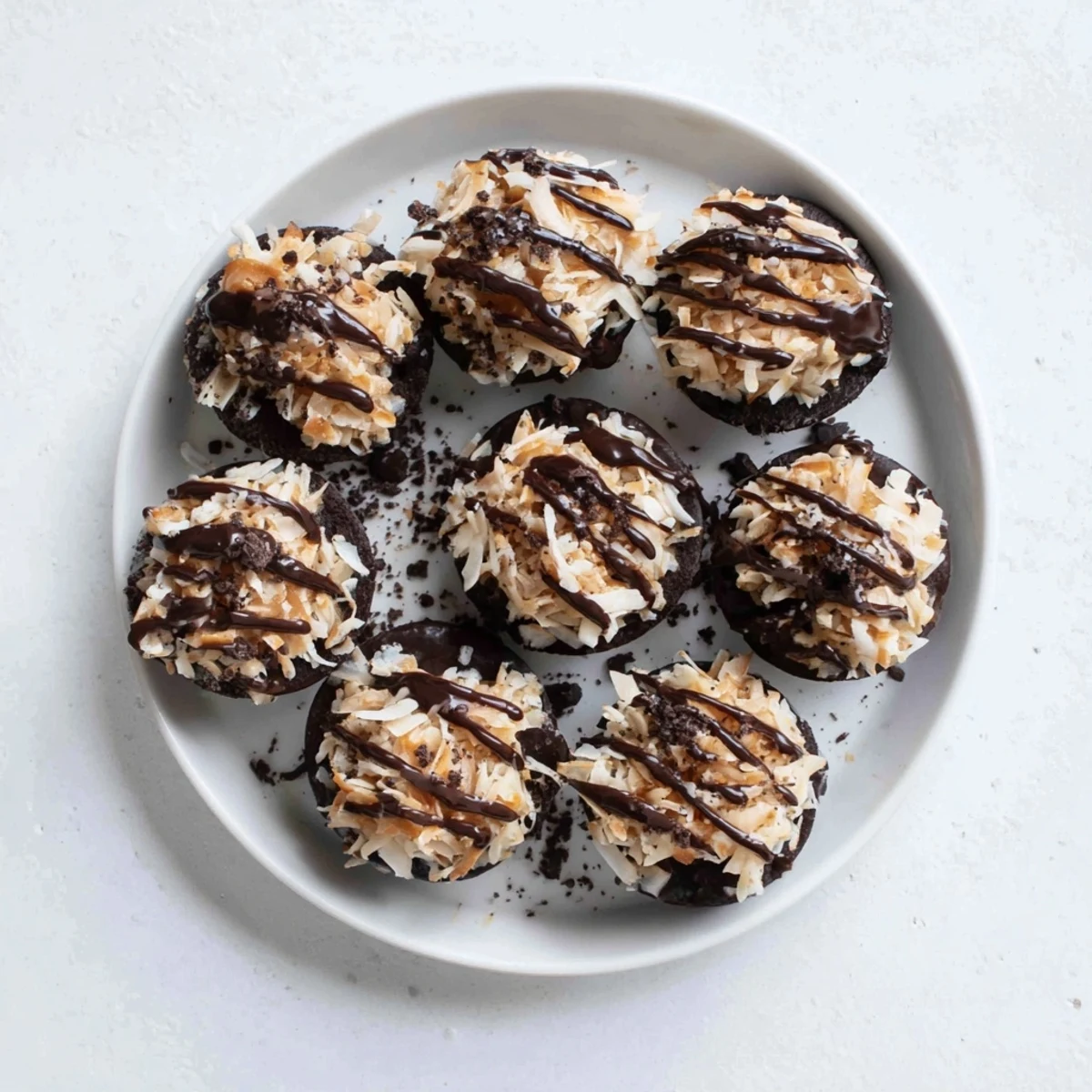 No bake Samoa bites topped with toasted coconut and caramel chocolate drizzle on white plate