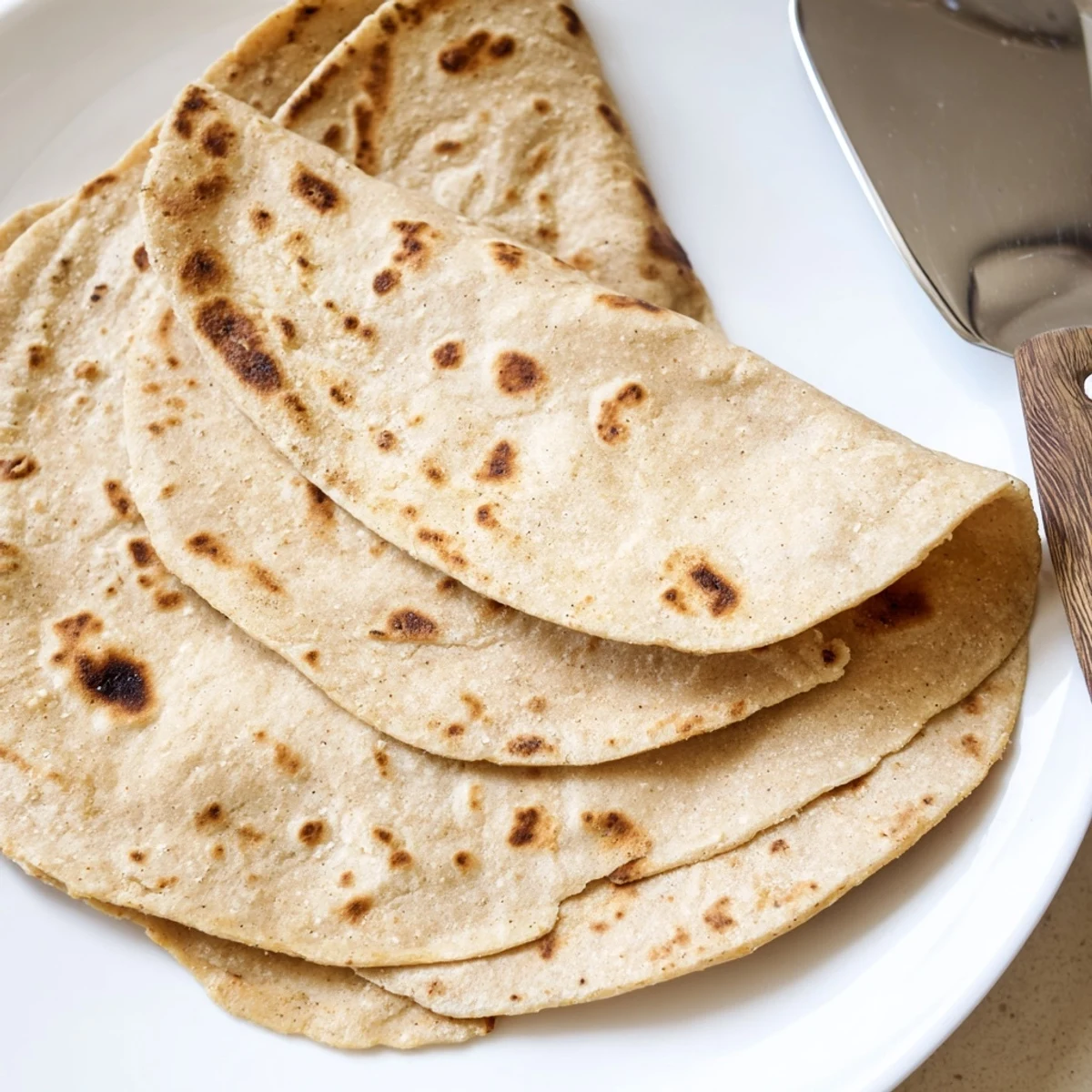 Golden brown sweet potato cassava tortillas stacked on a wooden board with visible char marks
