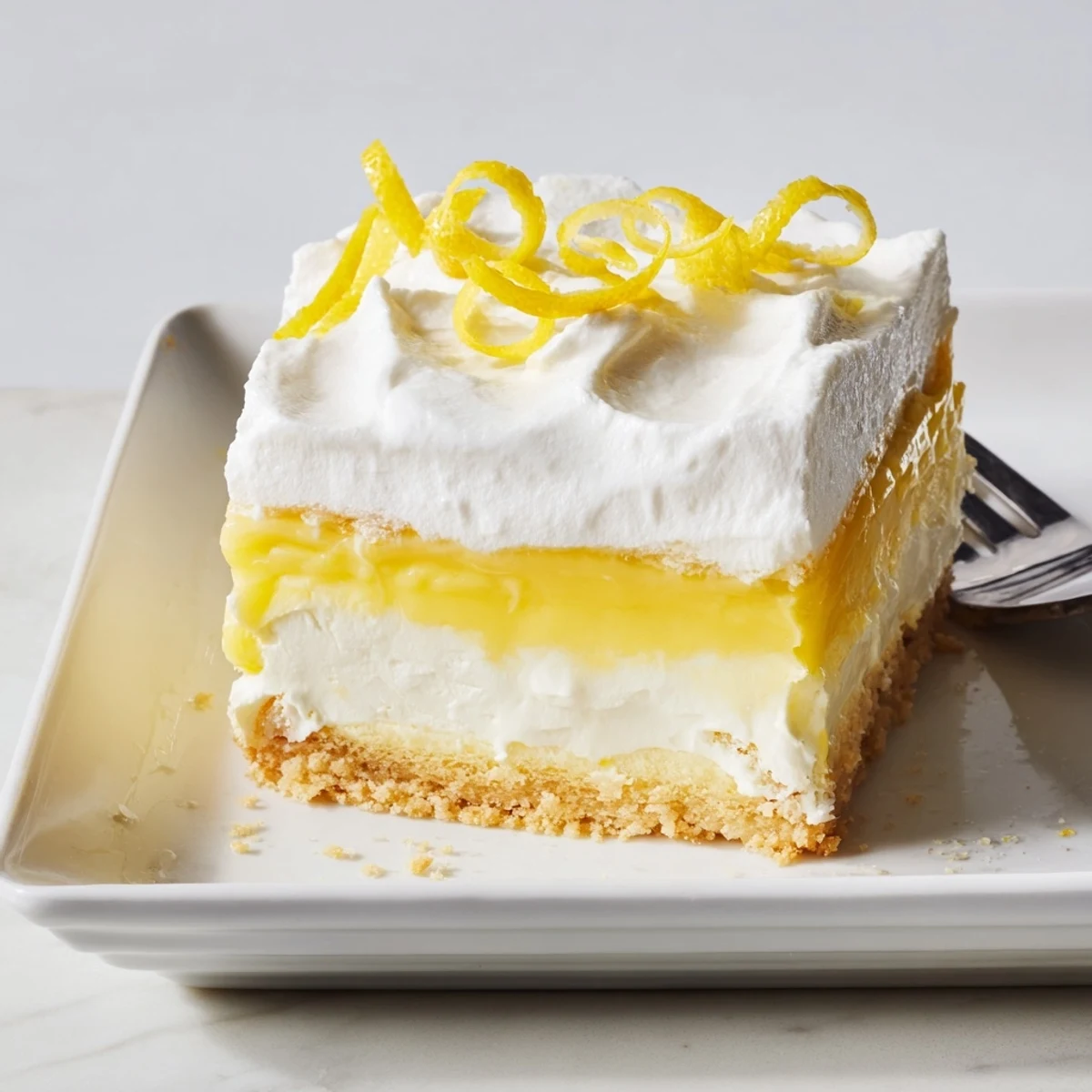 Fresh lemon zest garnished fluffy white topped lush cake beside whole lemon slices
