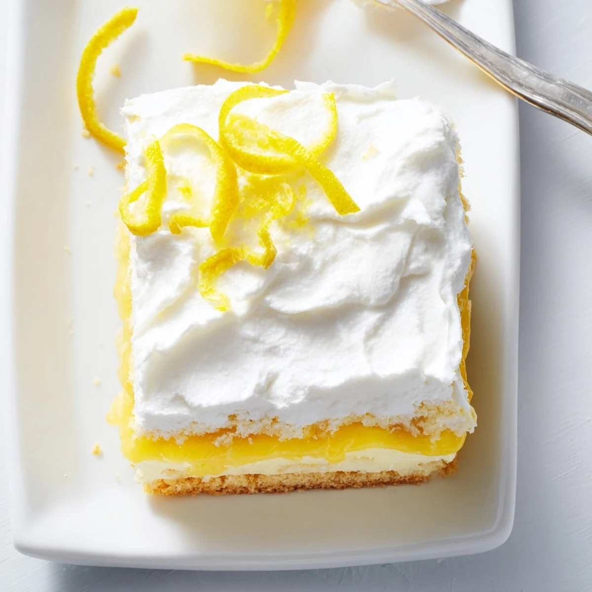 Golden lemon lush cake square revealing creamy layered cross-section on white dessert plate