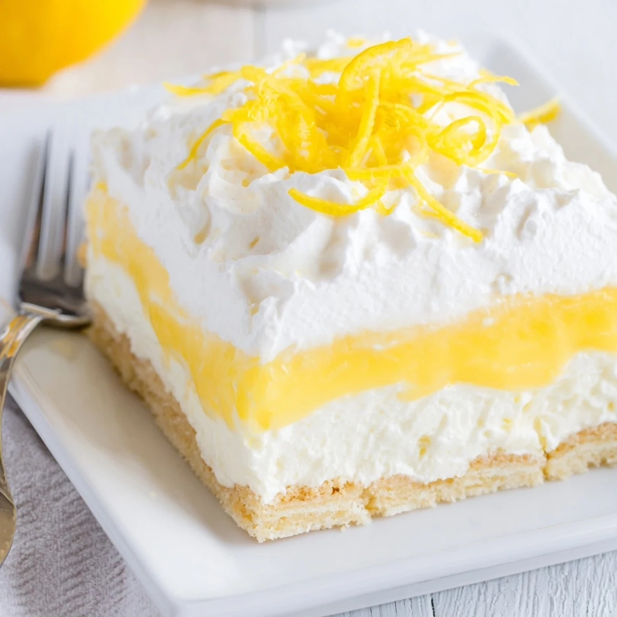 Buttery crust layered lemon lush dessert with whipped topping served in glass baking dish