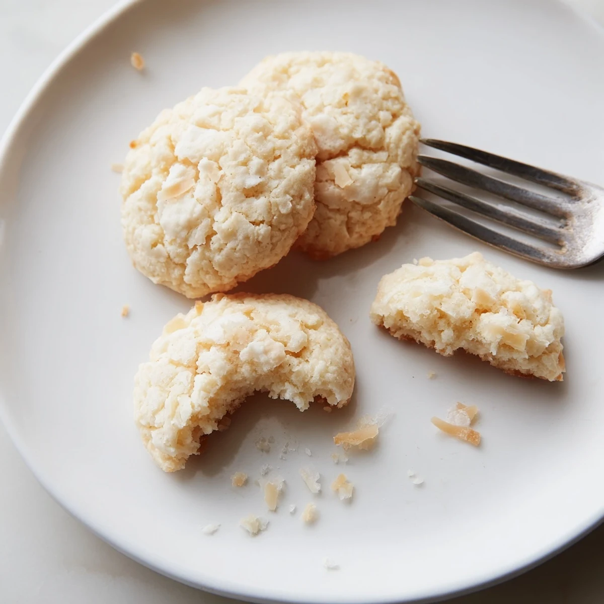 Golden coconut cookies with crisp edges and chewy centers on a cooling rack