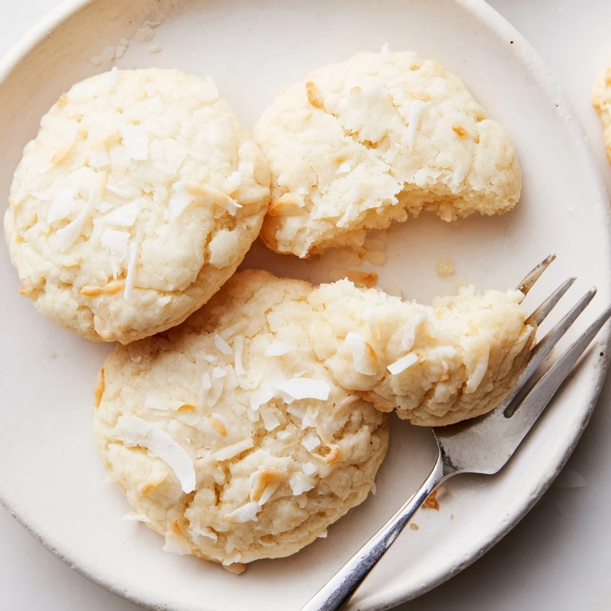 Soft and buttery coconut cookies arranged on a rustic parchment-lined baking sheet