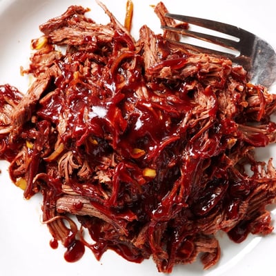 Tender shredded Slow Cooker BBQ Pulled Beef glistening in rich, smoky barbecue sauce